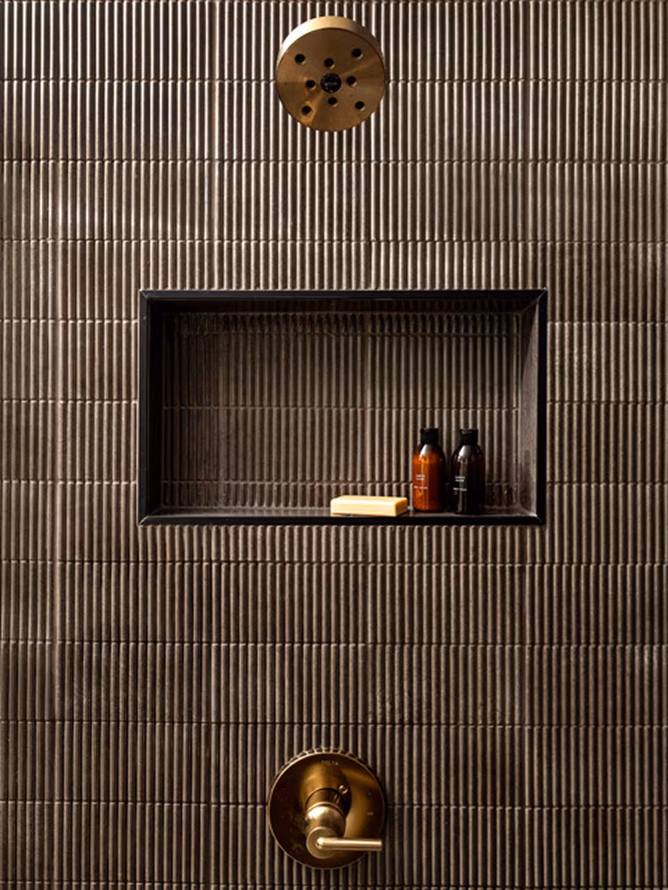 A recessed wall niche displays a pair of ceramic figurines, with a circular light fixture above and additional decorative elements below.